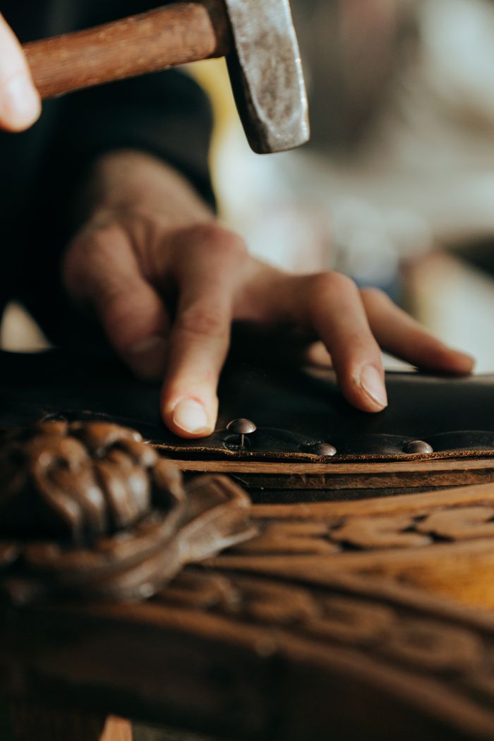 About Close-up of a craftsman working on vintage wooden furniture in a workshop setting.
